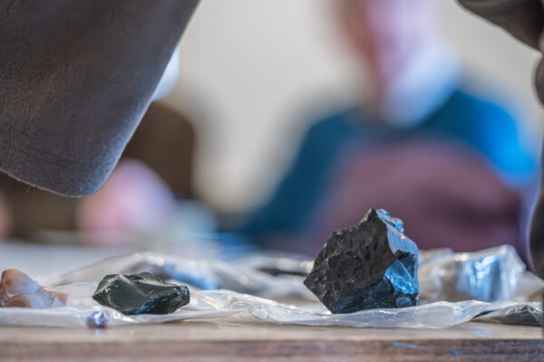 Large and small chunks of prehistoric lithics with tool marks sit on a table.