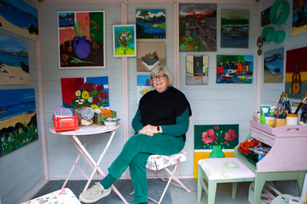 An artist in her home studio, surrounded by her work.