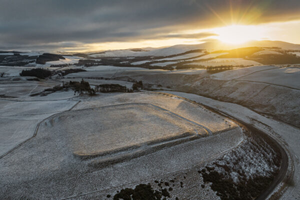 Aerial photograph of a snowy landscape with the rectangular outline of a Roman fort visible in the topography